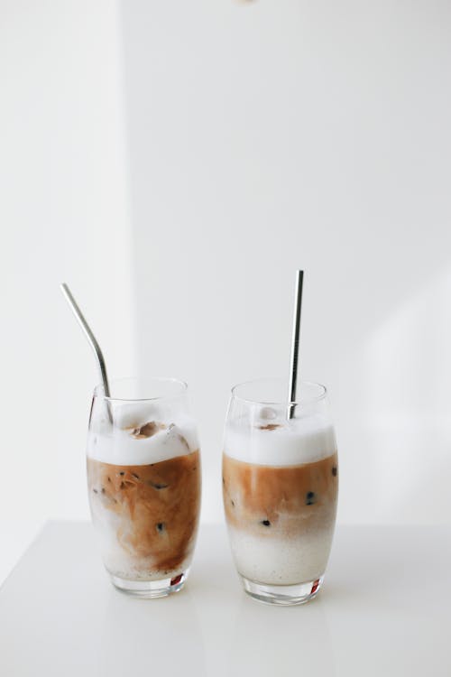 Two glasses of milky fruit cocktails with straws