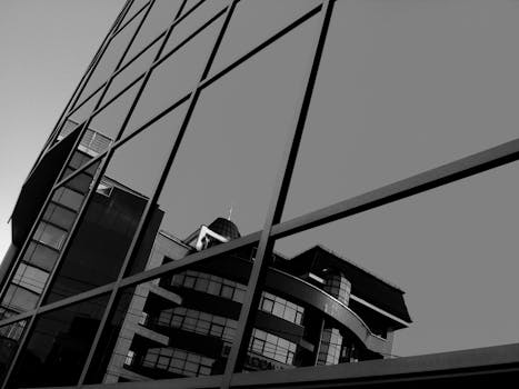 一座现代建筑的倒影映在玻璃窗上，以引人注目的黑白细节被捕捉到