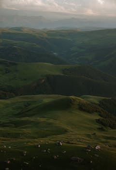 A tranquil aerial shot of lush green hills under a peaceful morning sky.