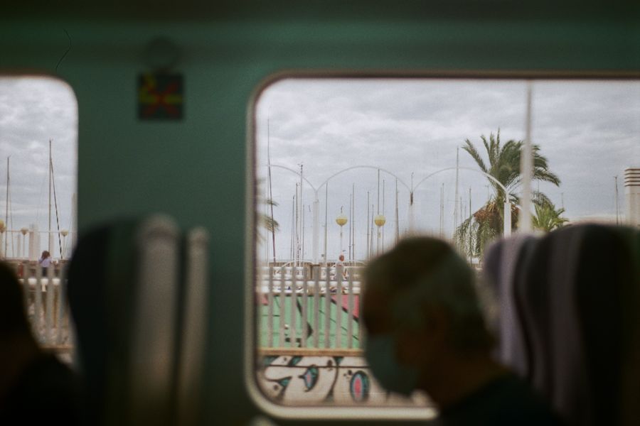 Silhouette of a person wearing a mask inside a train with a scenic Barcelona view.