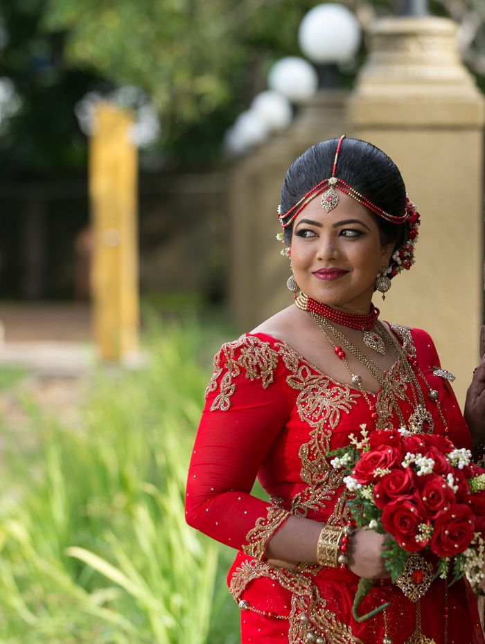 Sri Lankan homecoming bride in red and gold embroidered saree