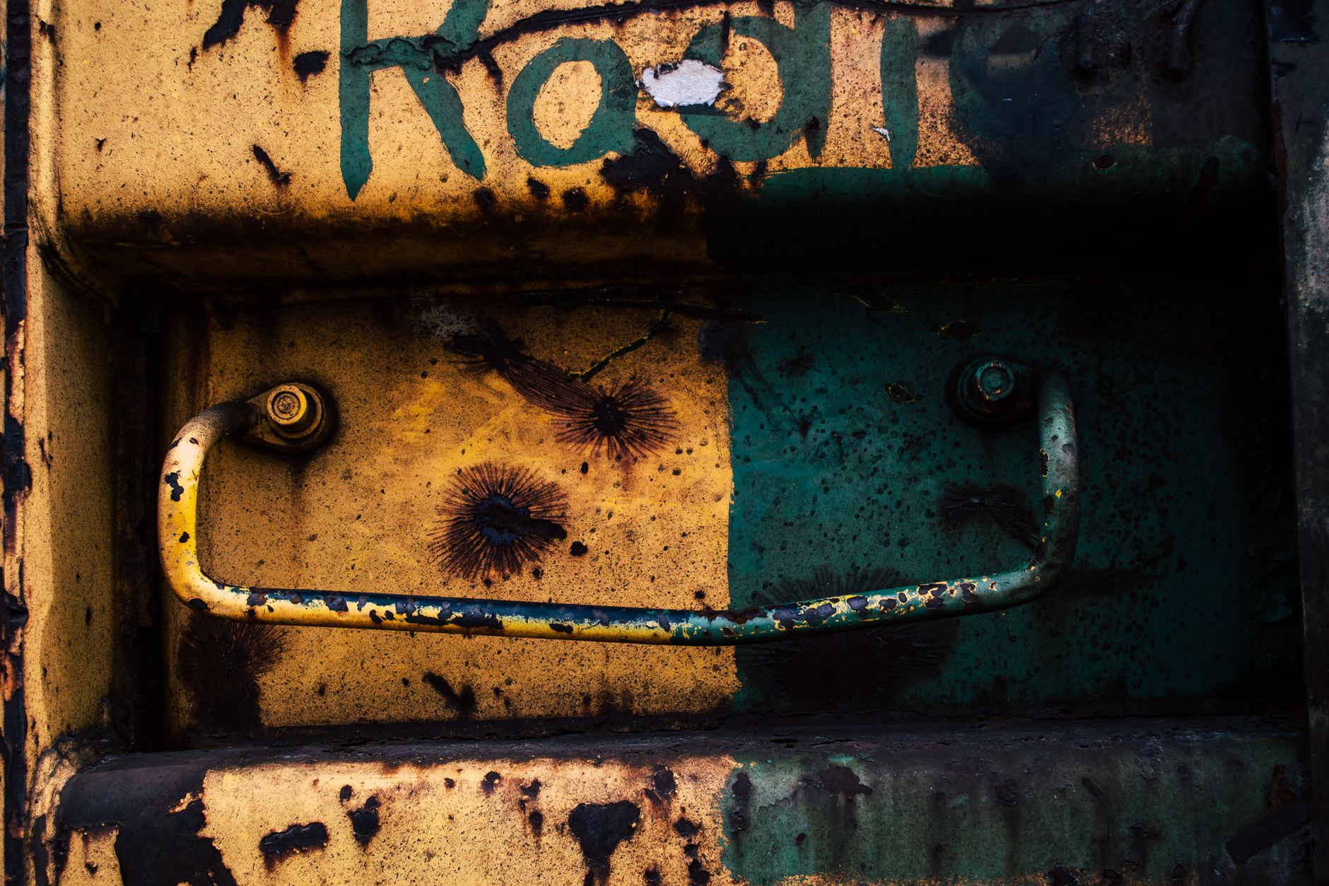 Close-up of a rusty metal door featuring graffiti and a peeling handle, embodying urban decay.