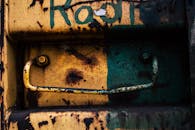 一扇生锈的金属门特写，门上有涂鸦和剥落的把手，体现了城市的衰败