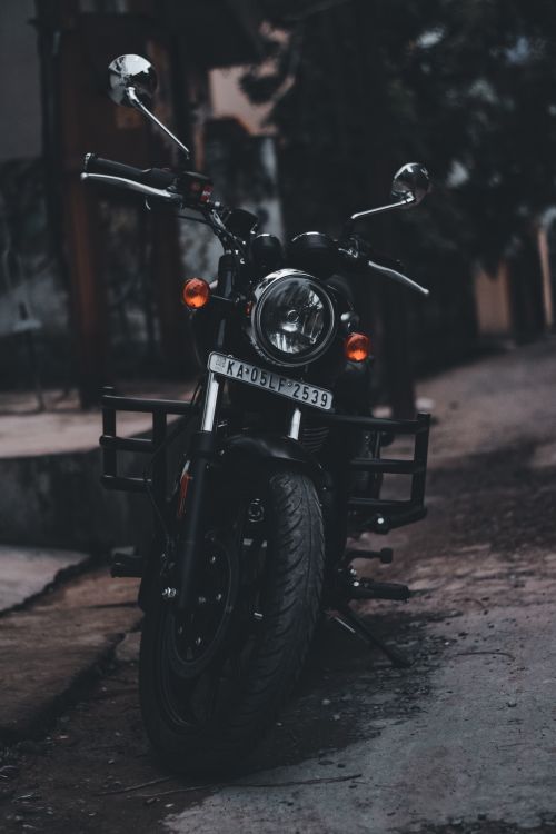Free Vertical photo of a parked motorcycle on a street, moody lighting. Stock Photo