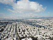 A stunning aerial view of Agia Paraskevi, Greece, showcasing the snow-covered cityscape and distant mountains.