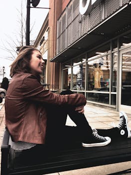 一位年轻女子面带微笑，坐在城市一家现代零售店外的长凳上