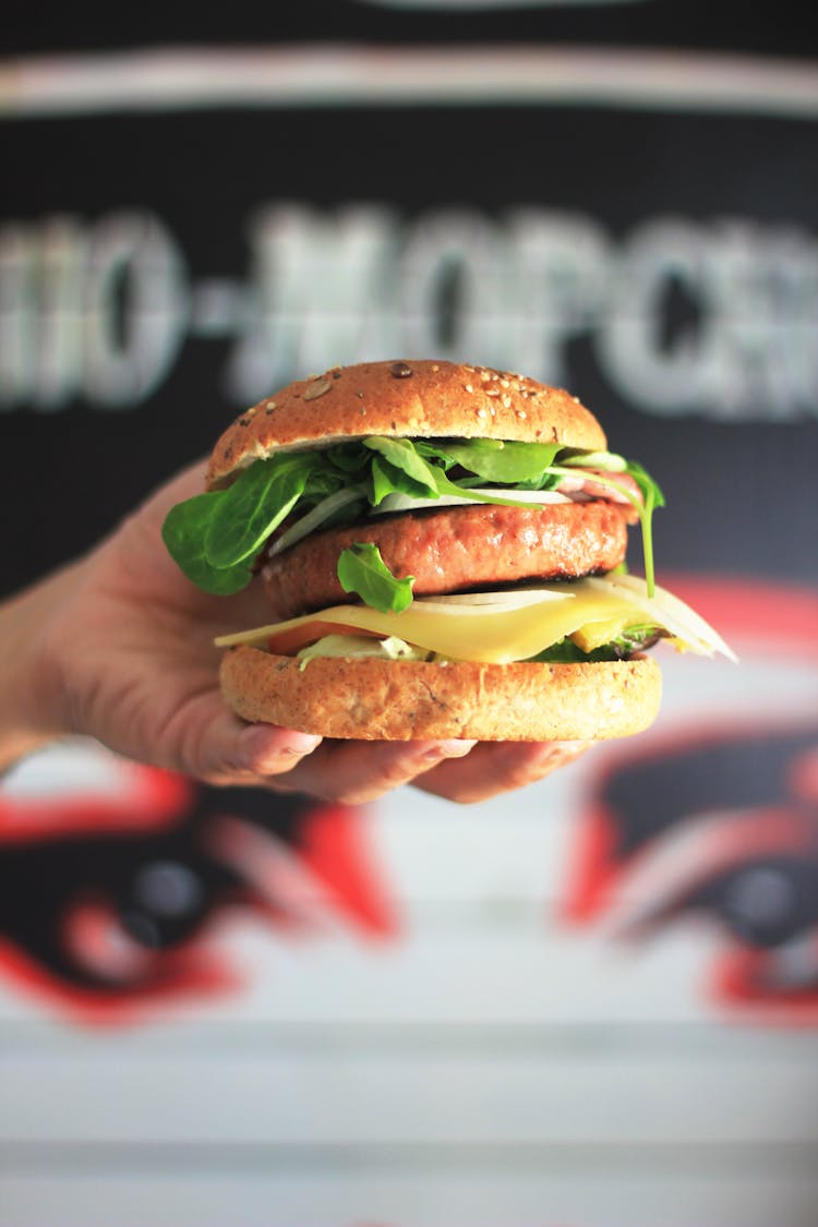 Photograph Of A Person's Hand Holding A Burger