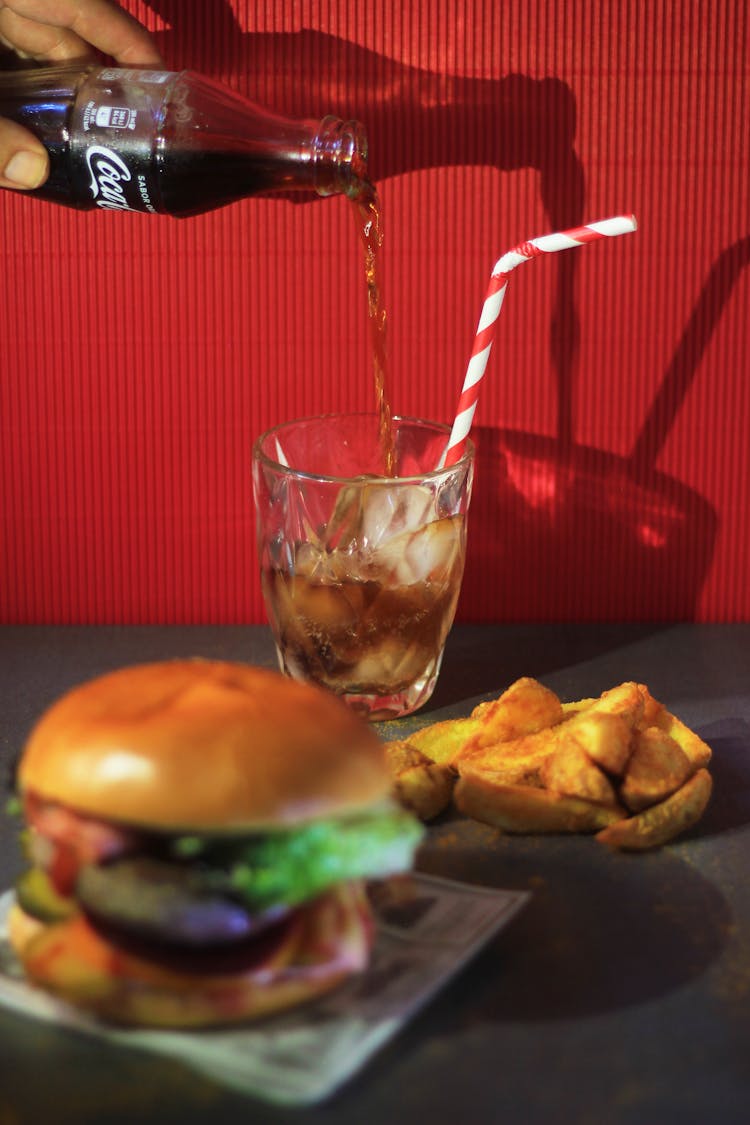 A Person Pouring A Carbonated Drink Into A Glass