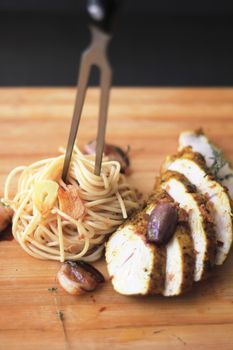 Plate of spaghetti with grilled chicken breast and roasted garlic for a gourmet meal.