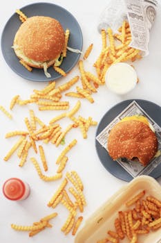 Flat lay of cheeseburgers and crinkle-cut fries on a white background, perfect for fast food themes.