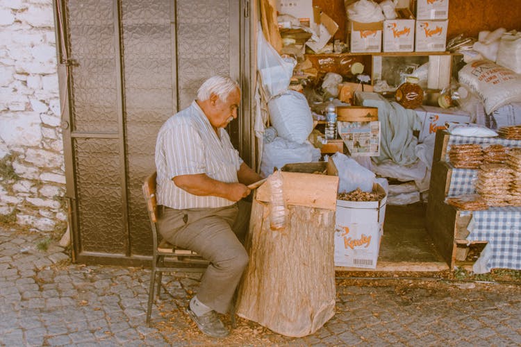 Eldery Man Using Hammer On The Pavement Outside His House