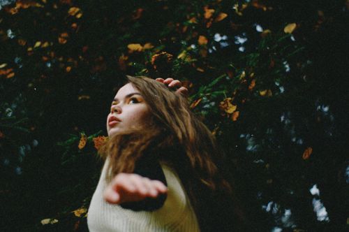 Free A young woman poses gracefully against a backdrop of autumn leaves. Stock Photo