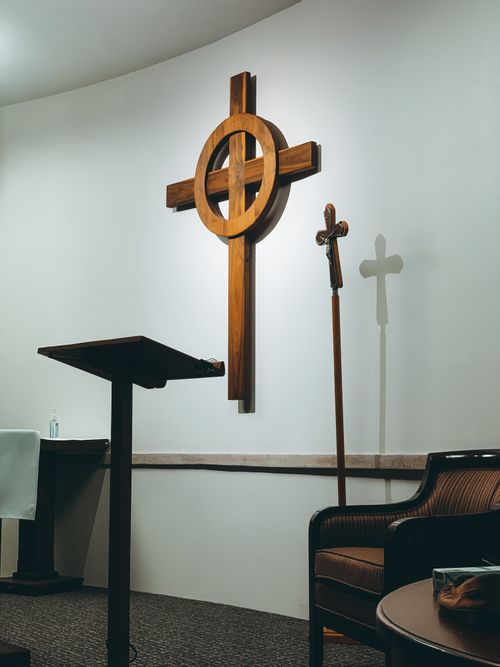 Free A serene church interior featuring a wooden cross with an altar and seating arrangement. Stock Photo