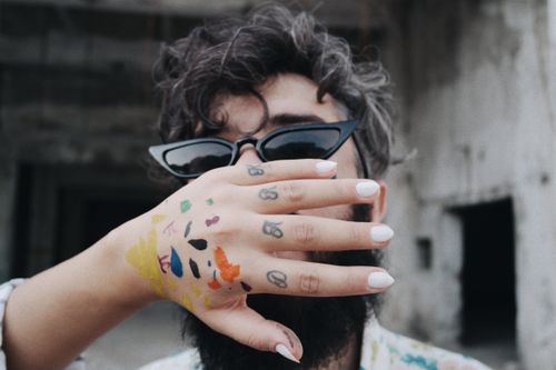 Free Close-up of a fashionable man with artistic hand tattoos, wearing sunglasses. Stock Photo