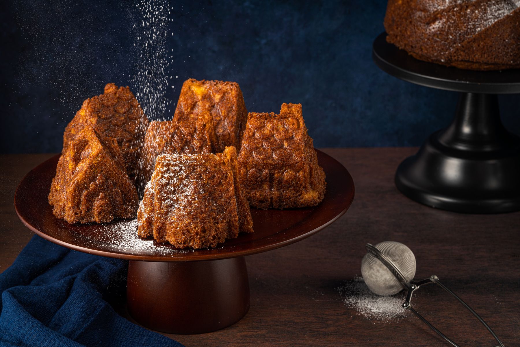 Small rustic cakes dusted with powdered sugar on a dark surface, photo by Skyler Ewing on Pexels