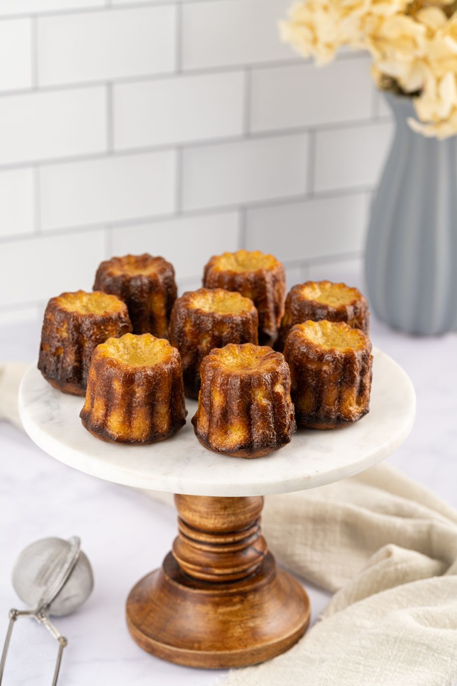 Caramelised cannelés on a marble stand