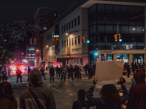 Free An urban protest at night with police and demonstrators on a city street. Stock Photo