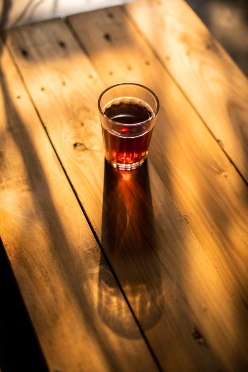 Free A warm cup of tea sits on a sunlit, rustic wooden table, basking in the natural light. Stock Photo