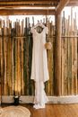 White long dress hanging in front of bamboo wall