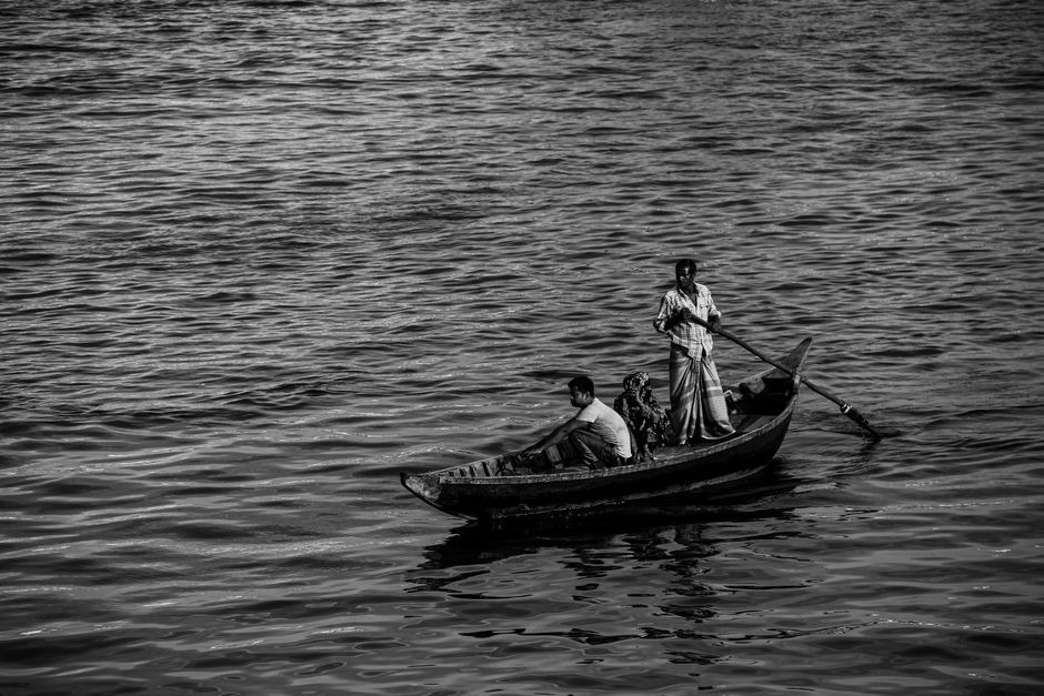 A tranquil black and white scene of people in a wooden boat on a lake.