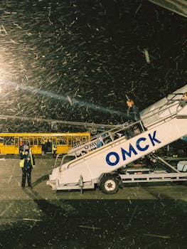 Passengers boarding a plane at night during snowfall, capturing a busy airport's lively environment.