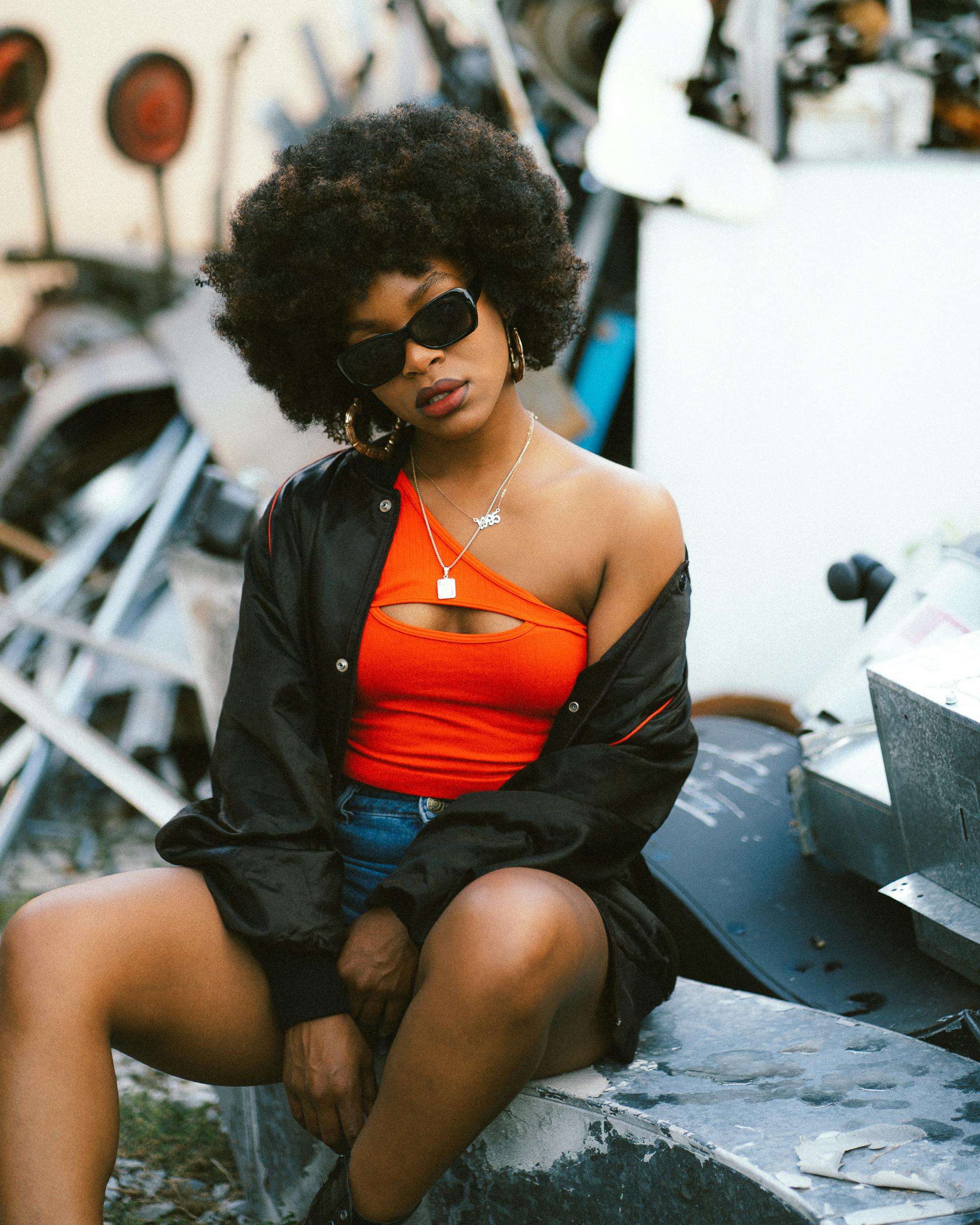 afro american young woman wearing sunglasses sitting on rubble block