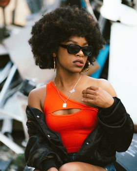 Teenage afro american girl wearing asymmetrical orange top and black jacket