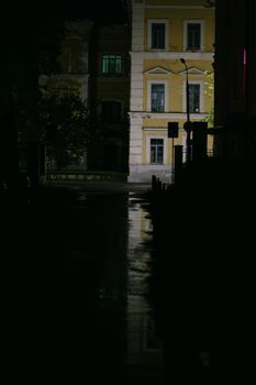 Dramatic street view at night featuring wet roads and lit buildings creating a moody ambiance.