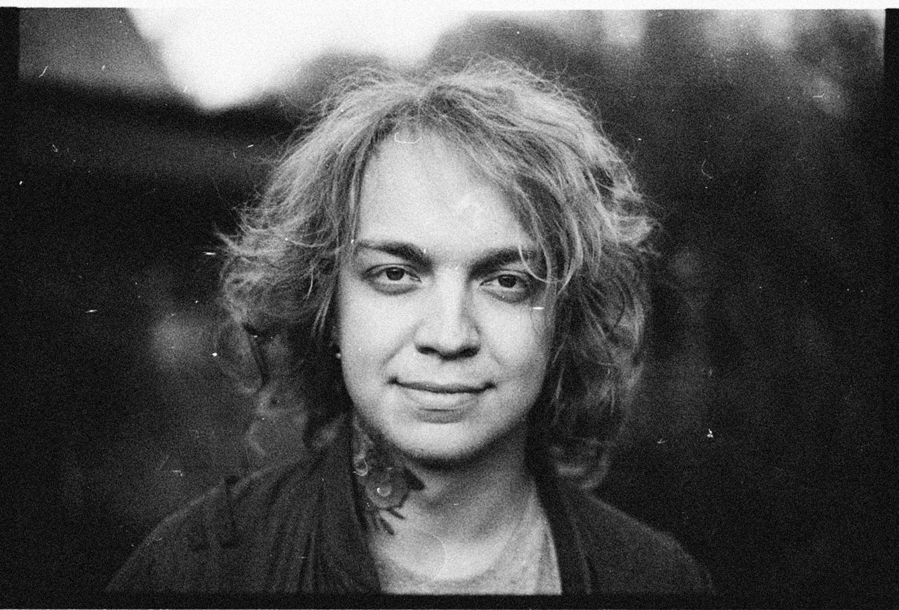 black and white close up portrait of a smiling young adult with curly