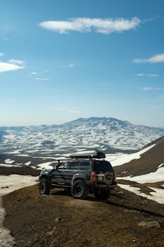 An off-road SUV navigating snowy mountain landscapes under a clear blue sky, perfect for adventure seekers.