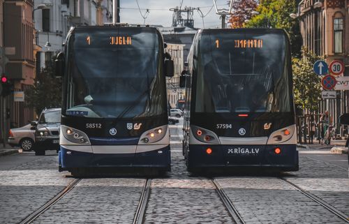 Free Two modern trams on cobblestone streets in Riga, Latvia, under a clear day sky. Stock Photo