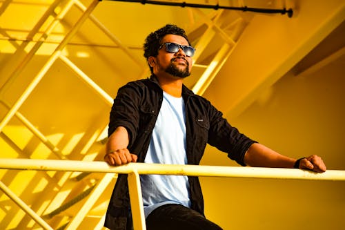 A Bearded Man Wearing Sunglasses with Hands on a Handrail