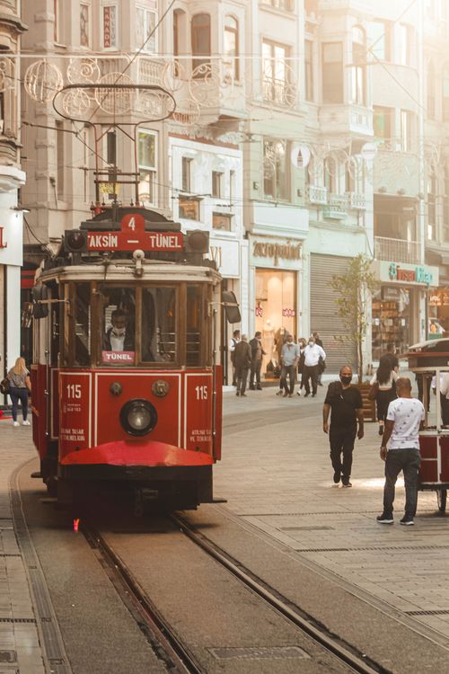 Free Vintage red tram moving through a lively street in Istanbul with people walking under bright lighting. Stock Photo