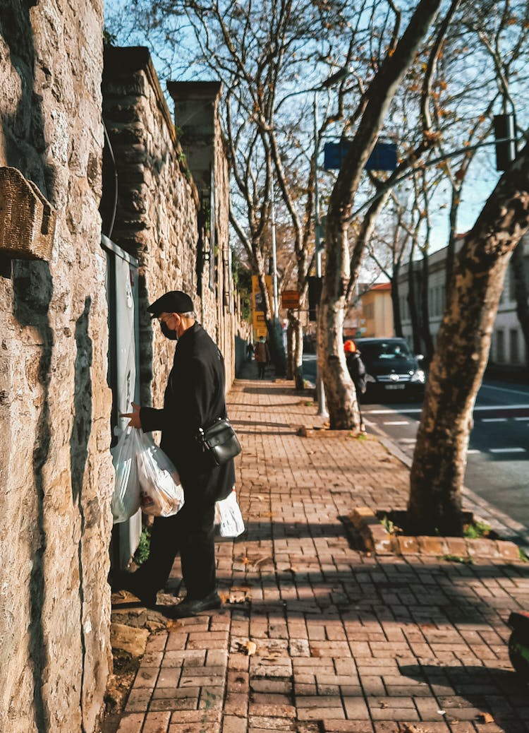 Photo Of A Man Opening A Door While Carrying Plastic Bags