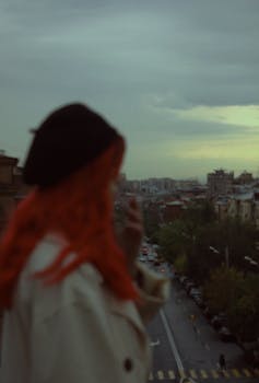 Artistic silhouette of a woman overlooking the cityscape of Yerevan at twilight, capturing a moody ambiance.
