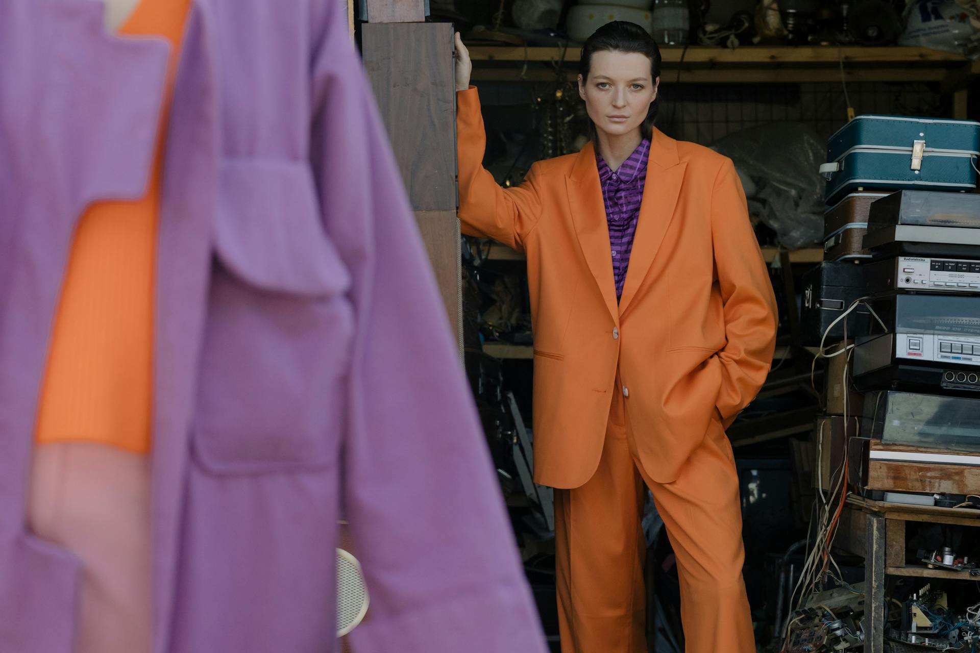 Fashionable woman poses in a vibrant orange suit indoors. Modern style and bold colors.