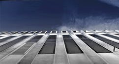 玻璃窗映衬着清澈蓝天的现代建筑立面低角度视图