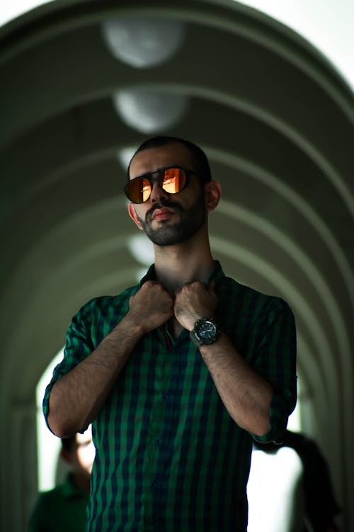 A Man in Plaid Shirt with Sunglasses Holding His Shirt Collar