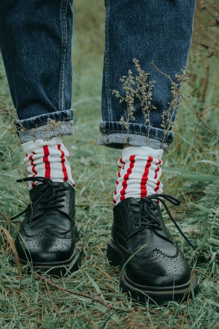 Close-up of stylish shoes and socks in a grassy meadow, showcasing trendy fashion.