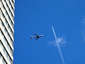 一架喷气式飞机在城市上空飞行，在晴朗的蓝天上留下了一条轨迹