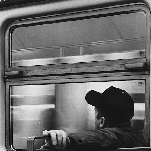 A Man in Black Cap Sitting on the Train