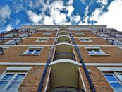 从低角度仰望现代化城市公寓楼，阳台映衬在蔚蓝的天空下