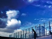 未来主义建筑外观采用玻璃面板和铁丝网，背景是戏剧性的蓝天