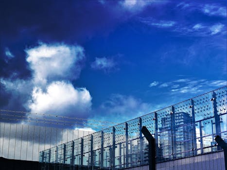 未来主义建筑外观采用玻璃面板和铁丝网，背景是戏剧性的蓝天