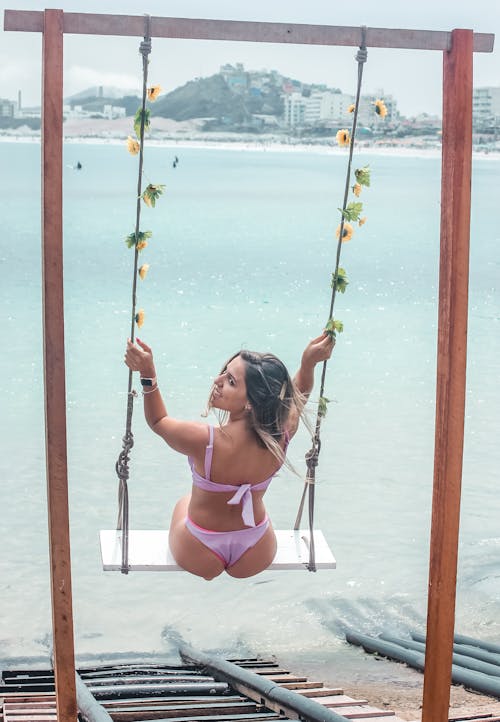 Photo of a Woman in a Bikini Riding a Swing
