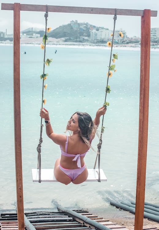 Photo of a Woman in a Bikini Riding a Swing