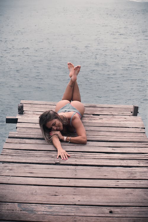 A Woman in Gray Bikini Lying on a Wooden Dock