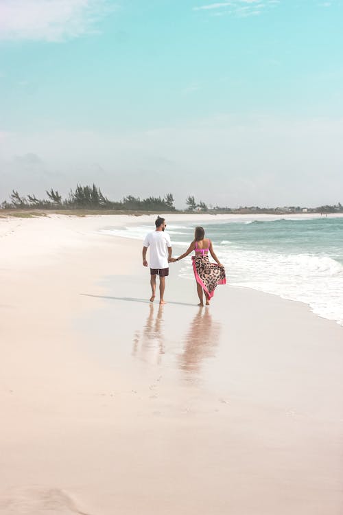 A Couple Walking at the Beach while Holding Hands
