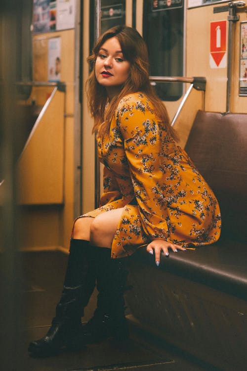 Woman in a Yellow Floral Dress Sitting on a Leather Seat