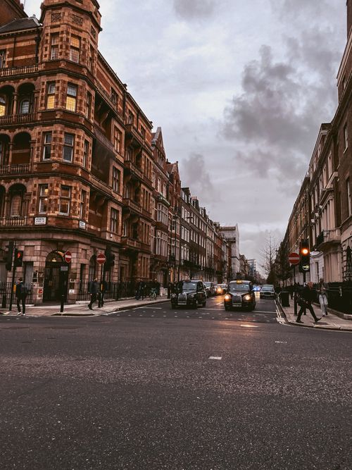 Free Cobbled street in London with classic architecture and taxis on a cloudy day. Stock Photo